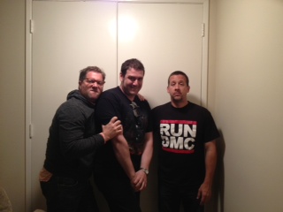 Three men posing in front of white door