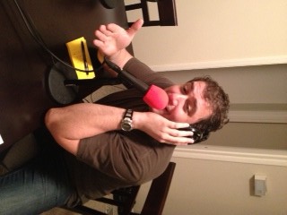 Person with headphones, thumbs-up, pink microphone